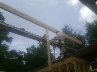 Carpenter setting a ridge beam over a new addition frame — Ice Dam Removal by Roofing Brothers in Adelanto