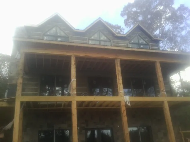 Dormers and porch framing on a large log home under construction — Roof Coating work by our crew in Adelanto