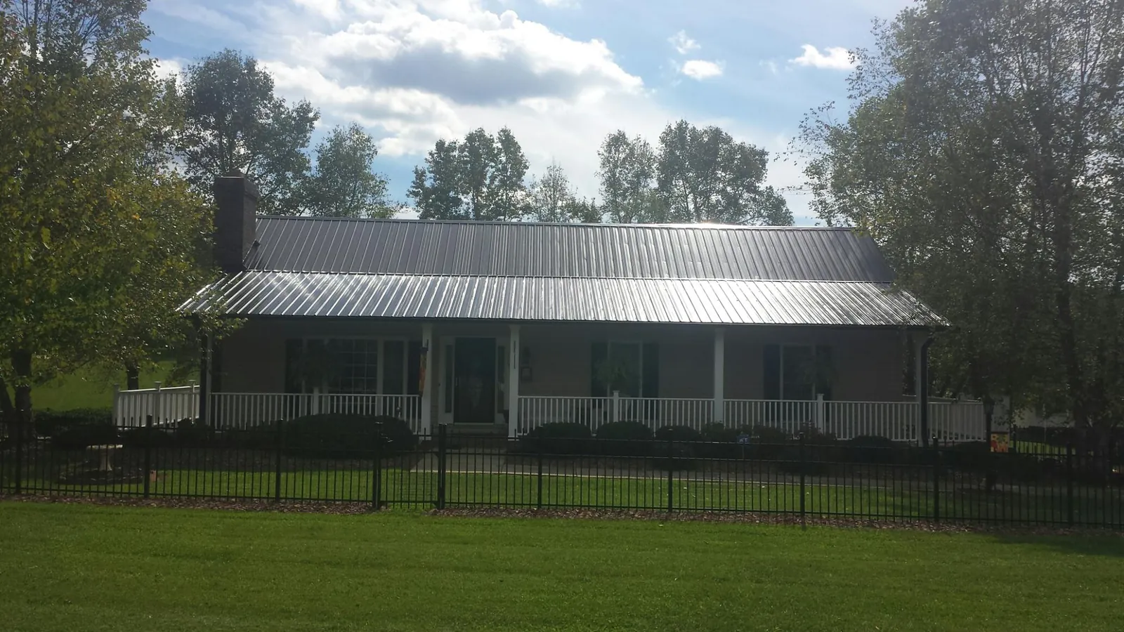 Gray metal roof on a brick ranch with a full width front porch — Gutter Guard Installation work by our crew in Adelanto