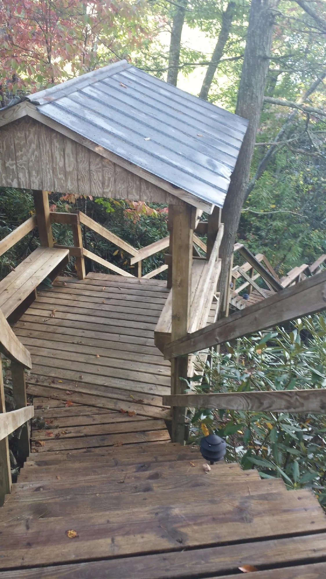 Metal roofed shelter over wooden steps on a wooded walkway — Skylight Repair & Installation work by our crew in Adelanto